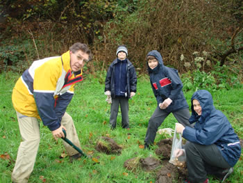 Photo of man digging while schoolboys watch